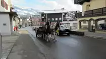Diese Pferdekutsche wird gerade von einem Automobil �berholt.(Kitzb�hel,26.12.2011)